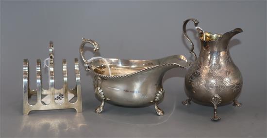 A Victorian engraved silver cream jug with scrolled handle and vacant cartouche, London 1856, a sauceboat and a toast rack, 11oz